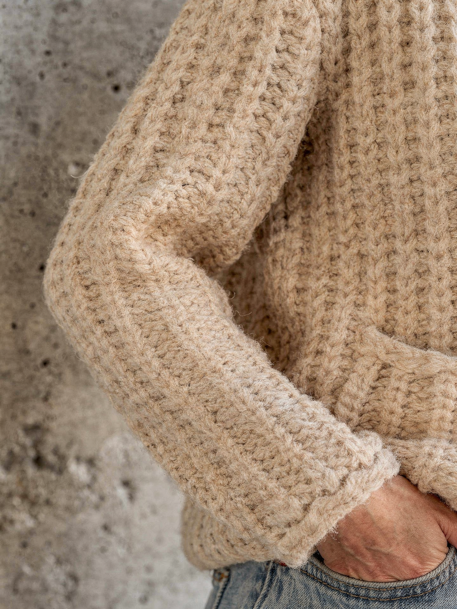 Close detail of the chunky knit texture and ribbed cuff